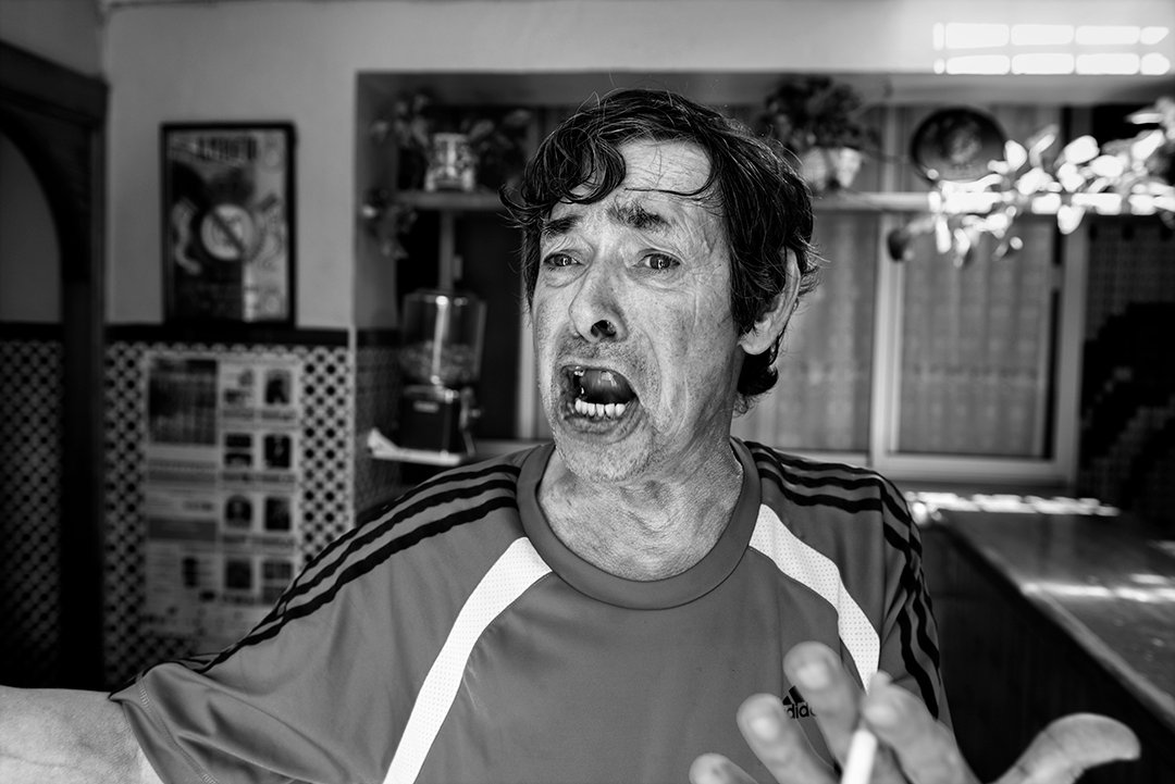 A man gesturing inside a bar.